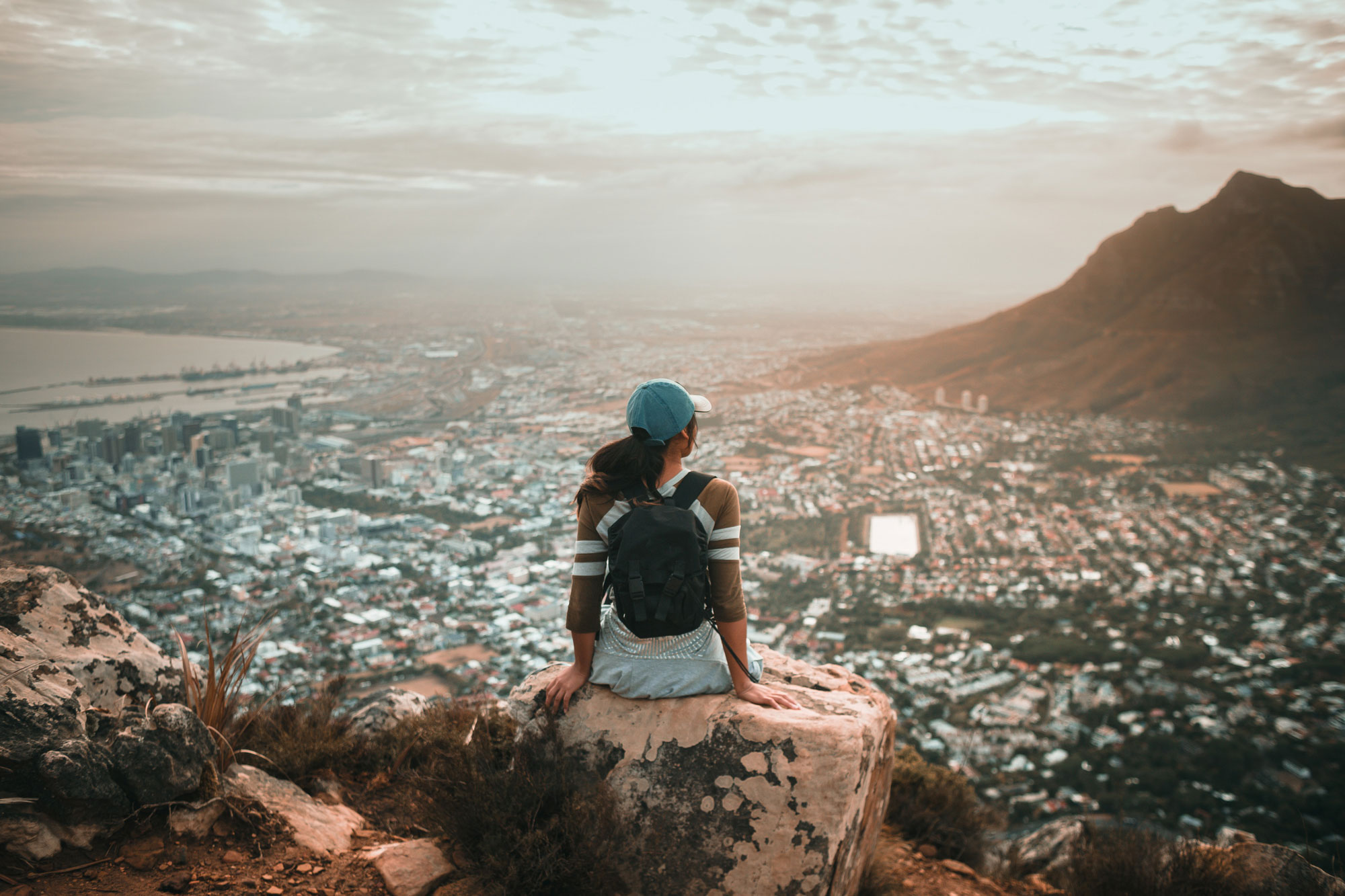 woman-cliff-seated-overlook-city.jpg